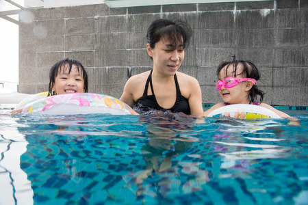 Asian Chinese family playing at the outdoor swimming pool on vacation during summertime.の写真素材