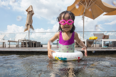 Asian chinese little girl plyaing at the outdoor swimming pool under sunshine day.の写真素材