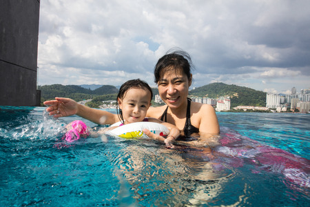 Asian Chinese mother and daugther playing at outdoor swimming pool on sunny dayの写真素材