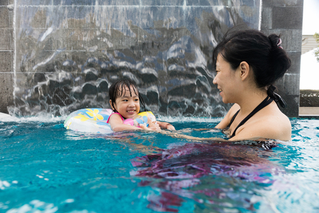 Asian Chinese mother and daugther playing at outdoor swimming pool on sunny dayの写真素材