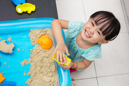 Happy Asian Chinese little girl playing kinetic sand in the living room at homeの写真素材