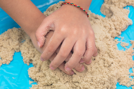 Child's hand close up playing kinetic sand at home indoors.の写真素材