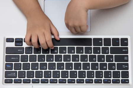 Close up aerial view of children hands typing on laptop keyboard.の写真素材