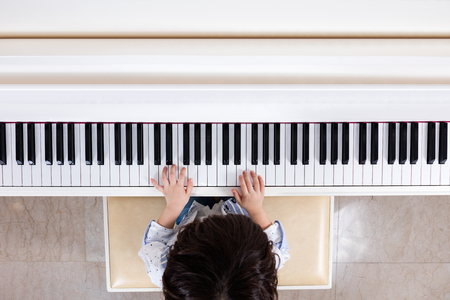 Aerial view of Asian Chinese little boy playing piano at homeの写真素材