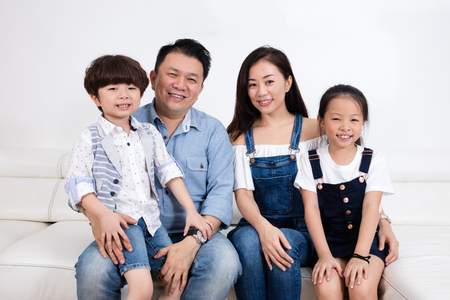 Happy Asian Chinese family sitting on the couch in the living room at home.の写真素材