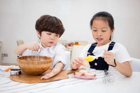 Asian Chinese little brother and sister preparing to bake cookies in the kitchen at home.の写真素材