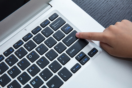 Close up aerial view of children hands pressing enter button of a laptop.