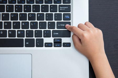 Close up aerial view of children hands pressing enter button of a laptop.の写真素材