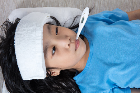 Asian Chinese little girl getting measurement for fever temperature at home.