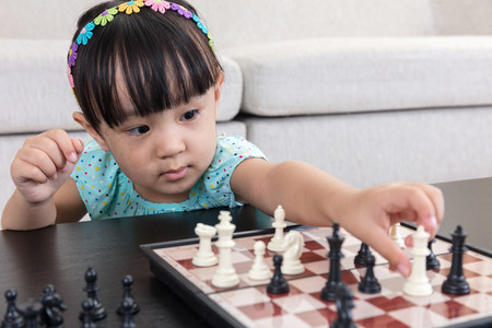 Aerial view of Asian Chinese little girl concentrating on chess next move in the living room at home.の写真素材