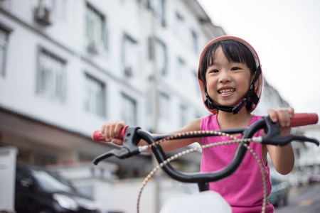 Asian Chinese little girl riding bicycle on tar road outdoor.の写真素材