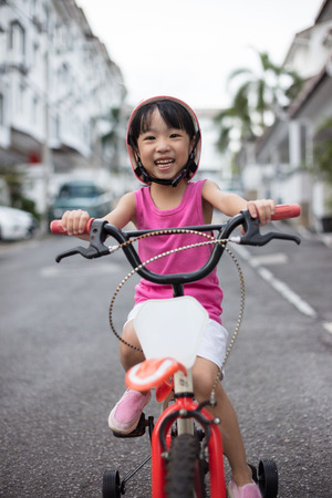 Asian Chinese little girl riding bicycle on tar road outdoor.の写真素材
