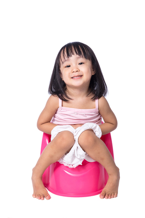 Asian chinese little girl sitting on chamberpot in isolated White Backgroundの写真素材