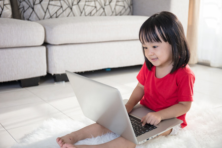 Asian Chinese little girl with laptop lying on the floor at home