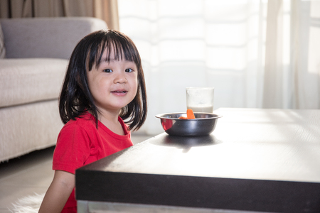 Asian Chinese little girl having breakfast with milk  in the living room at homeの写真素材