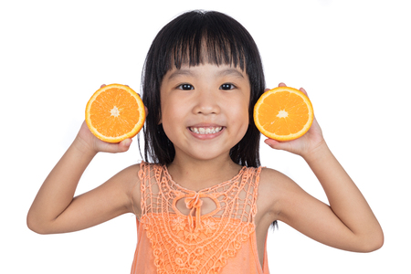 Happy Asian Chinese little girl holding orange in isolated white backgroundの写真素材