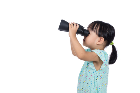 Asian Chinese little girl holding binoculars in isolated white backgroundの写真素材