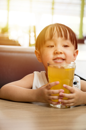 Asian little Chinese girl drinking lemon tea in outdoor cafeの写真素材