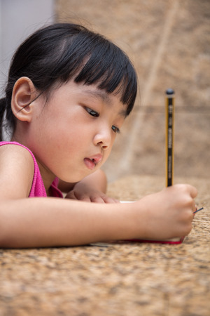 Asian little Chinese girl writing homework at homeの写真素材