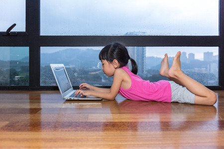 Asian little Chinese girl playing computer at homeの写真素材