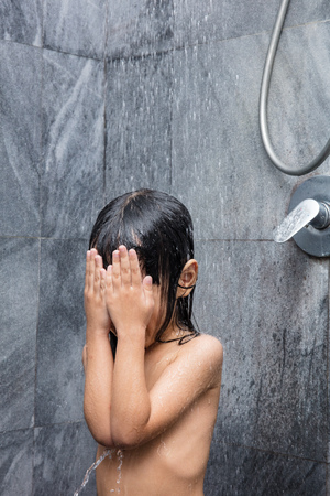Asian little Chinese girl taking a shower in the bathroom at homeの写真素材