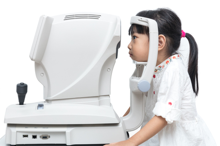 Asian Little Chinese Girl Doing Eyes Examination Through Auto refractometer in isolated White Backgroundの写真素材