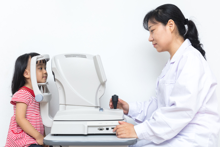 Asian Little Chinese Girl Doing Eyes Examination Through Auto refractometer in isolated White Backgroundの写真素材