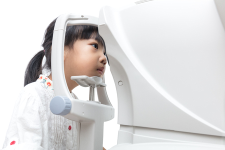 Asian Little Chinese Girl Doing Eyes Examination Through Auto refractometer in isolated White Backgroundの写真素材