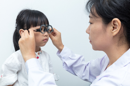 Asian Little Chinese Girl Doing Eyes Examination by ophthalmologist in isolated White Backgroundの写真素材
