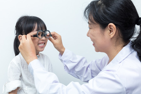 Asian Little Chinese Girl Doing Eyes Examination by ophthalmologist in isolated White Backgroundの写真素材