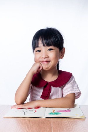 Asian Little Chinese girl reading a painting book in isolated white backgroundの写真素材