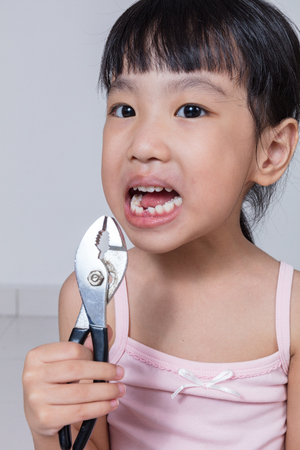 Asian Chinese little girl holding pliers and showing the gap in isolated white backgroundの写真素材