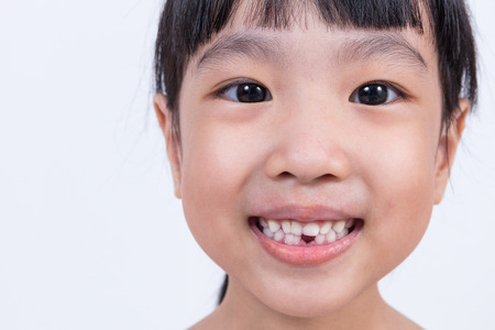 Happy Asian Chinese little girl with toothless smile in isolated white backgroundの写真素材
