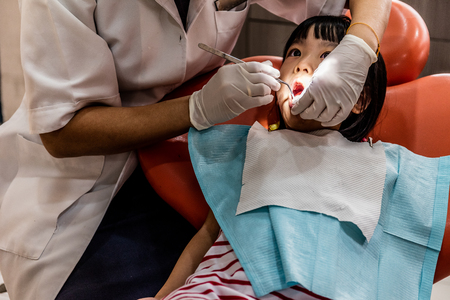 Asian Chinese little girl lying down for tooth extraction at dental clinicの写真素材