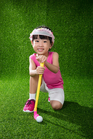 Asian Chinese little girl playing golf on green grassの写真素材