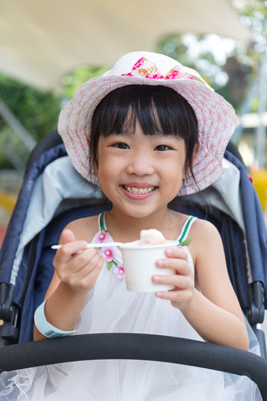 Asian Chinese little girl eating ice cream at outdoor parkの写真素材