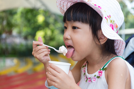 Asian Chinese little girl eating ice cream at outdoor parkの写真素材