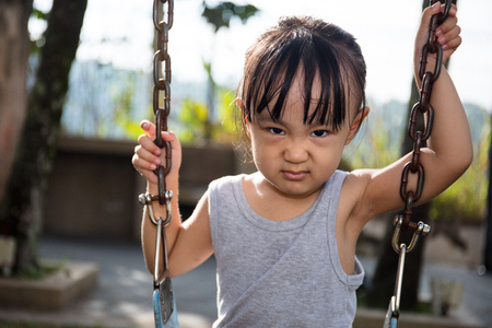 Asian little Chinese girl playing swing at outdoor parkの写真素材