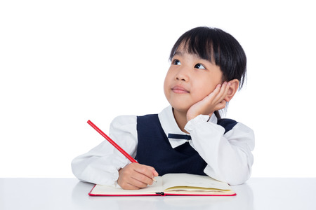 Asian Little Chinese girl writing homework in isolated white backgroundの写真素材