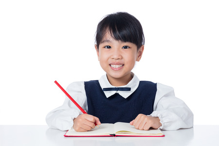 Asian Little Chinese girl writing homework in isolated white backgroundの写真素材