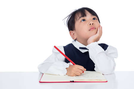 Asian Little Chinese girl writing homework in isolated white backgroundの写真素材