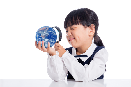 Asian Little Chinese Girl Looking At Globe Through Magnifying Glass in isolated White Backgroundの写真素材