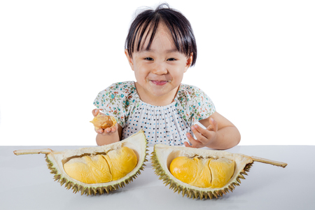 Asian Chinese little girl eating durian fruit in isolated white backgroundの写真素材