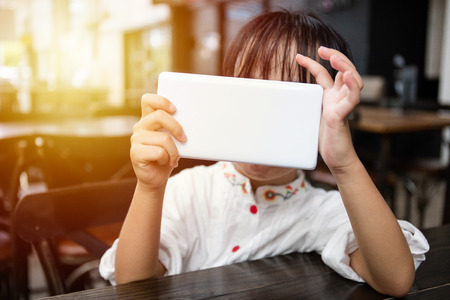 Asian Chinese little girl playing smartphone at outdoor cafeの写真素材