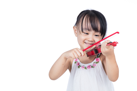 Asian chinese little girl playing violin in isolated white backgroundの写真素材