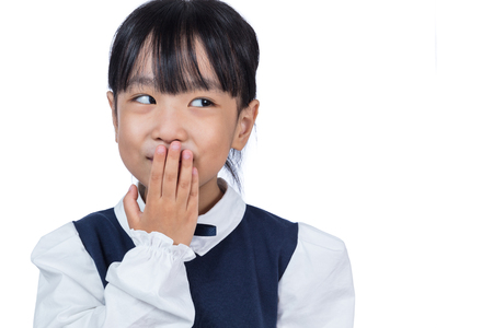 Asian Chinese little girl laughing and covering her mouth in isolated white backgroundの写真素材
