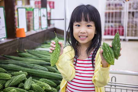 Asian Little Chinese Girl choosing vegetables in supermarketの写真素材