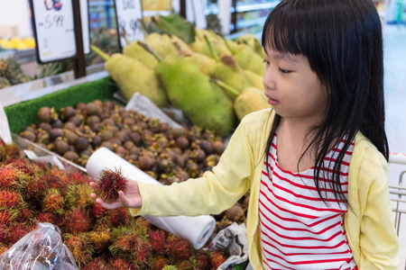 Asian Little Chinese Girl choosing fruits in supermarketの写真素材