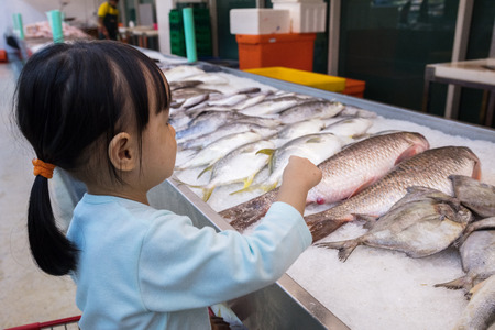 Asian Little Chinese Girl choosing seafood in supermarketの写真素材