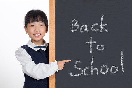 Asian Chinese little girl standing beside blackboard in isolated white background